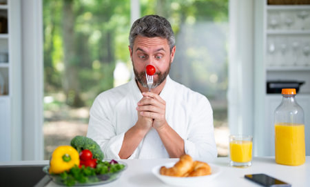 Man eat breakfast in the kitchen on a morning. Guy eat vegetables for a healthy meal in his kitchen in the morning. Man eat healthy food in cozy kitchen. Morning breakfast in the modern kitchen.の写真素材