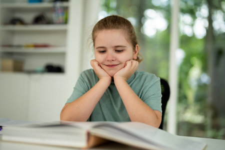 Kid reading book at home. Kid book studying. Child opening book indoors. Kid earning with books. Boy focused on textbook lesson. Clever teen reading storybook. Kid studying book at desk.の写真素材
