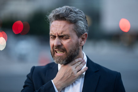Tired business man outdoors suffering from a headache. Man relieving pain from a migraine. Financial...