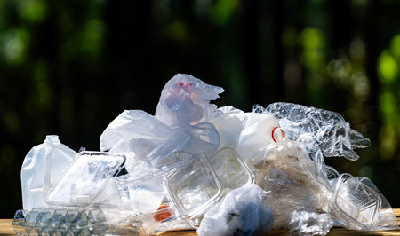 Plastic pollutes on green nature. Waste harms wildlife habitats. Garbage spreads across natural...