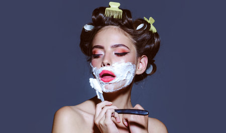 Young woman shave moustache with razors. Beauty woman shaving foam on face. Attractive girl is having a shave. Waxing epilation threading and hair removal cream. Laser upper lip hair removal concept.の写真素材