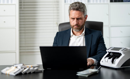 Businessman counting cash at his office desk. Office worker managing money at work. Accountant checking currency. Financial success. Banker organizing banknotes. Man counting money at office.の写真素材