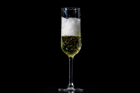 Champagne splash. Pour of sparkling wine. Champagne glass on black background. Sparkling wine. Wineglass with champagne. Splash of champagne for festive celebration. Pouring sparkling wine.の写真素材