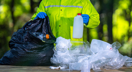 Volunteers collect rubbish. Cleaning nature helps reduce pollution. Hands in gloves pick up plastic...