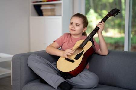 Kid playing guitar. Child practicing guitar music in living room. Kid learning guitar indoors. Boy with guitars during music lesson. Kid playing acoustic guitar. Child practicing songs.の写真素材