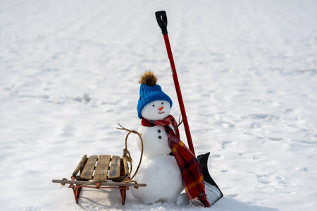 Snowman in winter outdoor park. Snow man in winter nature background. Snowman for festive winter greeting banner. Snowman with scarf and hat.の写真素材