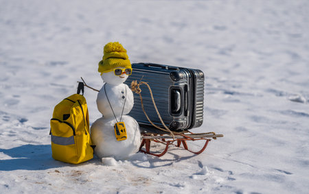 Snowman with suitcase ready for winter vacation. Snow man traveler holding travel bag. Funny snowman on snowy holiday adventure. Snowman tourist with backpack. Winter journey with a festive snowman.の写真素材