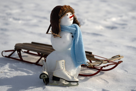 Snowman with scarf and winter hat outdoors. Snow man with carrot nose. Snowman standing on snowy...