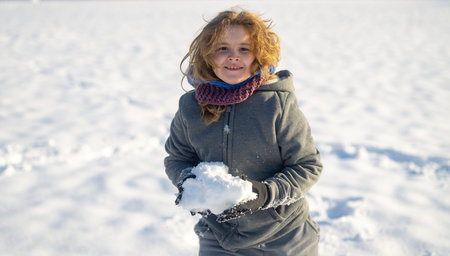 Child throwing snow outdoor. Kid in winter. Happy children playing in snow. Child enjoying winter...