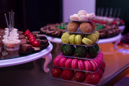 Colorful macarons and desserts on elegant buffet table. Luxury sweets and macarons served at festive event. Delicious macarons. Dessert table with macarons. Sweet dessert. French macaron.の写真素材