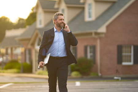 A realtor hands keys to a homeowner. Real estate agent inspects an apartment interior. Agent explains property financing. A real estate broker stands confidently outside a residential building.の写真素材