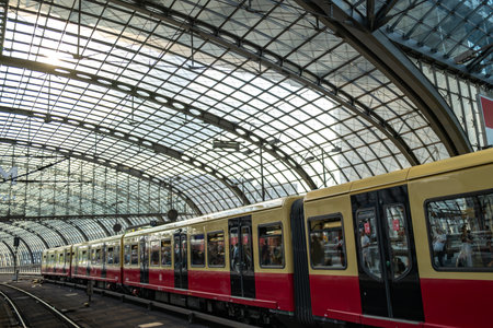 Train waiting at Berlin station. Modern glass roof architecture. Urban transportation hub. Reflection of passengers in windows. Travel scene in Germany.の写真素材