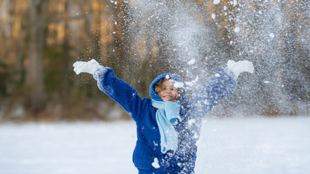 Child playing in snow. Snowball fun for children. Child portrait in winter hat. Kids laughing and...