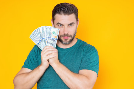 Man hold money on yellow studio isolated background. Portrait of rich man with money dollar bills. Successful guy with dollar banknotes. Rich millionaire holding money.の写真素材