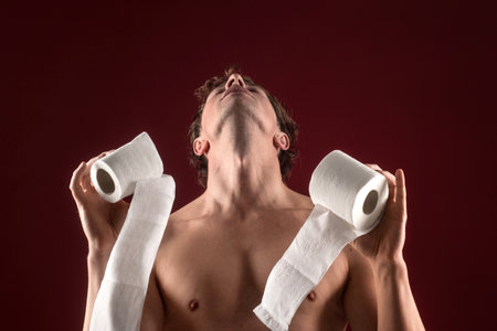 Fun toilet concept. A man holds toilet paper like a restroom emergency. Funny toilet. Restroom panic with tissue rolls. Comedic toilet supply shortage. Humorous restroom.の写真素材