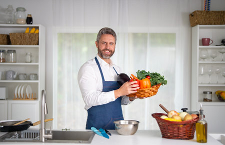 A man chops ingredients for homemade meal in kitchen. A chef preparing a vegetarian dish in the...