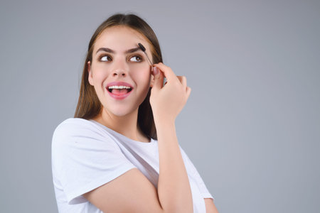 Eyebrow shaping, woman combs eyebrows with a brus. Eyebrow line. Makeup and cosmetology concept. Female model with long eyelashes and thick eyebrows. Perfect shaped brow.の写真素材