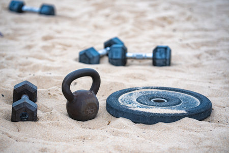 Natural workout. Gym weights in park. Summer training. Barbell and dumbbell set. Exercise outdoors in nature. Kettlebell with heavy weights. Park workout with dumbbells. Weightlifting on the beach.の写真素材