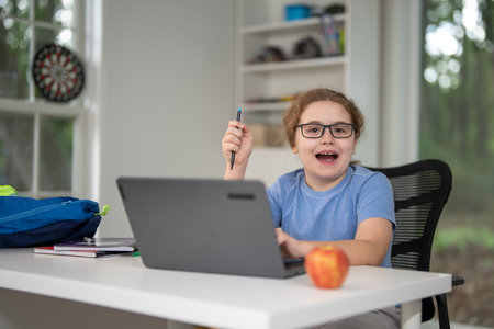 Kid learning at home with laptop and books. Child learn online using laptop at desk. Learning with homework in child room. E-learning on laptop. Kid learning at home. Back to school.の写真素材