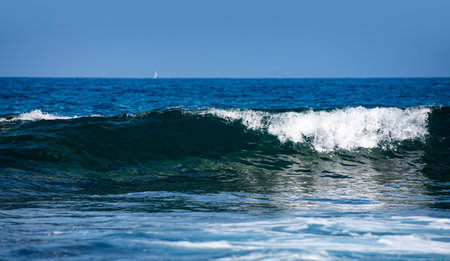 Rolling ocean waves movement. Wave background. Soft sea waves. Blue sea waves reflect sunlight. Abstract ocean texture. Transparent sea waves with foam sparkle.の写真素材