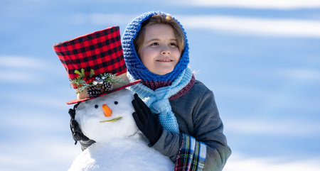 Child enjoying snow winter fun and making snowman. Child playing with snowman. Winter children fun.の写真素材