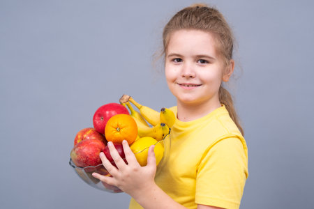 Kid showing colorful mix of healthy fruits. Kid holding bowl full of fruits. Healthy lifestyle and kids nutrition concept. Smiling kid showing organic fruit mix. Portrait of child with healthy food.の写真素材