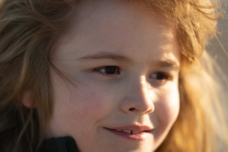 Kid face macro. Warm light on child face. Soft focus portrait of kid. Kid looking away. Child dreamer. Dreamy teen child. Daydreaming kid.の写真素材