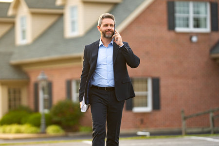 Real estate agent front of a house. Realtor estate agent shows residential building in suburbs. Businessman celebrates home ownership. Real estate manager.の写真素材
