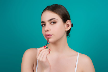 Woman lipstick makeup portrait. Beautiful female with red pink lips over studio background. Portrait beautiful woman applying lipstick, red lip gloss.の写真素材