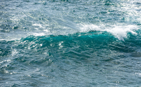 Close up of ocean wave with white foam. Sea splash and turquoise water. Ocean waves in motion. Blue wave rolling with reflections. Texture of seawater and foam. Powerful sea wave background.の写真素材