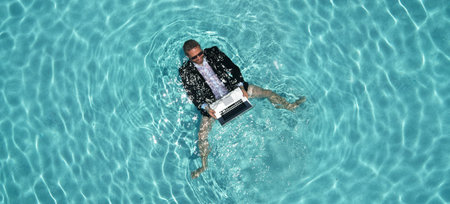 Man in suit in swimming pool. Freelancer with laptop floating in pool. Fun business and summer vacation. Crazy businessman working in pool. Summer free business. Remote job summer concept.の写真素材
