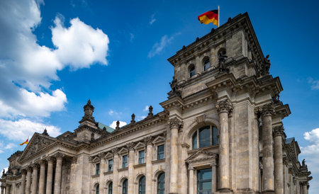 German flag over Reichstag. Corner view of Reichstag Berlin. Historic government architecture. German landmark with flag. Historic Reichstag architecture in Berlin. Political symbol of Germany.の写真素材