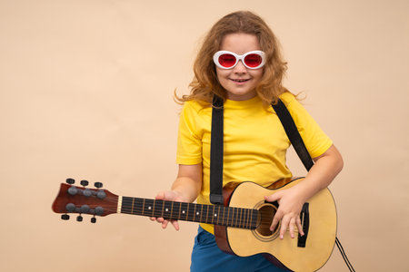 Kid with guitar plays music. Child play guitar isolated on studio background. Kid music talent. Music kids education. Teen guitarist to music. Acoustic guitar inspires players. Kid learning guitar.の写真素材