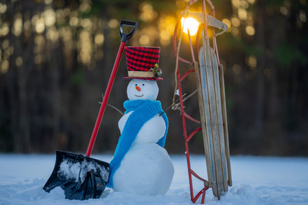 Winter design with snowman and snow shovel. Winter design with cute snow man and sled. Creative winter card with snowman. Winter design with snowman decoration. Snowman with shovel on snowy field.の写真素材