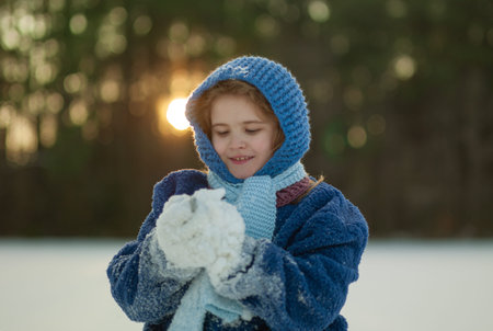Child playing snowball fight in winter forest. Happy kid enjoying outdoor snowball battle. Cute...