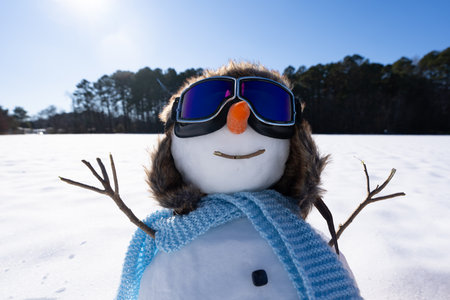 Snowman aviator preparing winter gift delivery. Holiday snow scene with toy plane and snowman. Christmas snowman pilot with wooden airplane. Cute Christmas snowman with pilot hat.の写真素材