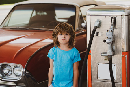 Happy child near vintage car outdoors. Portrait of boy enjoying car ride. Childhood travel moments with classic auto. Kid driver and retro car. Outdoor lifestyle with child and vintage vehicle. Fun road trip with kids.の写真素材