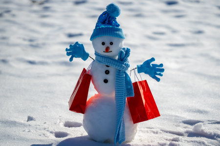 Snowman with shopping bags during a winter sale. Winter shopping fun. Snowman promoting Christmas gift. Snowman with winter discount sale. Winter seasonal sales. Snowman presenting Christmas gift.の写真素材