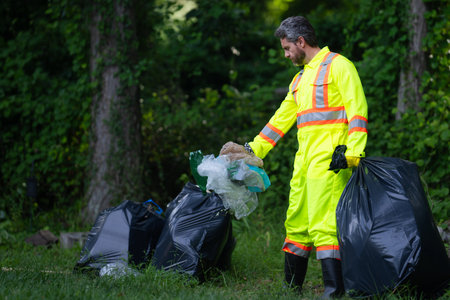 Volunteer in rubber gloves with trash bag clean up garbage on forest outdoor. Eco, environment conservation. Recycle pollution. Man collecting garbage and plastic trash. Save environment.の写真素材