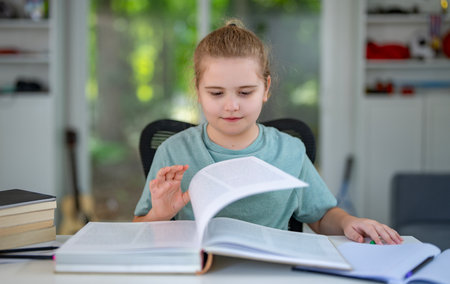 Kid reading a book at home. Child enjoying storybook in cozy room. Little boy reading books in bedroom. Cute girl reading favorite story at home. Young kid learning with book in living room.の写真素材