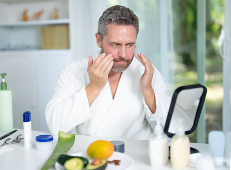 Beauty man enjoying spa facial at home. Middle-aged male receiving a rejuvenating spa treatment for healthy skin. Spa and wellness routine. Anti-aging treatments in a spa setting.の写真素材
