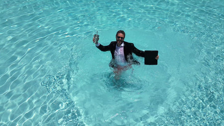 Summer business. Funny business man in suit used laptop in swimming pool. Fun business humor. Freelancer with laptop floating in summer water. Fun business and summer vacation crazy businessman.の写真素材