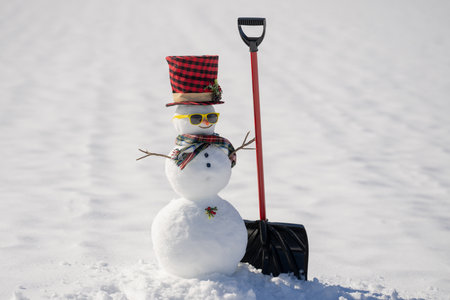 Cute snowman outdoors. Snowman with sled. Snowman clearing snow. Snowman winter decoration.