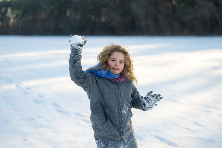 Child winter action shot. Winter outdoor playtime kid. Kid playing snow games. Laughing child in...