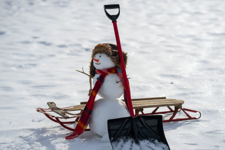 Snowman with shovel clearing the snowy path. Winter design with snowman and snow shovel. Snowman...
