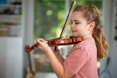 Kid playing violin at home. Child practicing classical music indoors. Young violinist. Kid with...