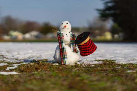 Snowman fading away as warm spring weather arrives. Warm winter weather. End of winter, hello spring. Winter snowman disappearing in early spring. Winter and spring seasons change.の写真素材