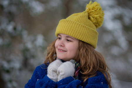 Happy kid exploring a snowy winter forest. Winter day portrait of a child having fun. Child touching snowflakes in a winter landscape. Kid with rosy winter cheeks outdoors.の写真素材