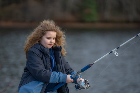 Child focused on fishing rod. Kids fishing day. Kid holding fishing rod outdoors. Child relaxing with fishing.の写真素材