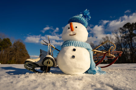 Cute snowman outdoors on a bright winter day, warm scarf and hat, cheerful holiday atmosphere, suitable for Christmas cards, seasonal greetings, and winter decor.の写真素材